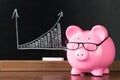 Pink piggybank with glasses on desk