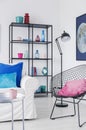 Pink pillow on black stylish metal armchair in bright cosmos inspired interior with metal furniture and white sofa with pillows,