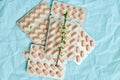 Pink Pills Arranged Neatly With White Blossoms on a Textured Blue Background