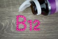 Pink pills forming shape to B12 alphabet on wood background Royalty Free Stock Photo