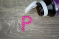 Pink pills forming shape to P alphabet on wood background Royalty Free Stock Photo