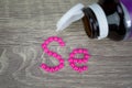 Pink pills forming shape to Se alphabet on wood background Royalty Free Stock Photo