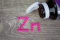 Pink pills forming shape to Zn alphabet on wood background Royalty Free Stock Photo