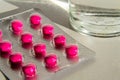 Pink pills with glass of water on white background Royalty Free Stock Photo