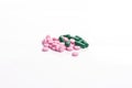 Pink pills and green capsule against white background Royalty Free Stock Photo