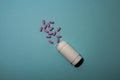 Pink pills poured from an open white bottle on a blue background, medicine Royalty Free Stock Photo