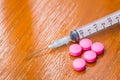 Pink Pills and syringe on wood table Royalty Free Stock Photo