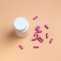 Pink pills, tablets and white bottle on orange background Royalty Free Stock Photo