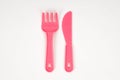 Pink plastic baby fork and knife on a white background Royalty Free Stock Photo