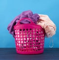 Pink plastic basket full of clothes and linen on a blue background Royalty Free Stock Photo