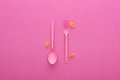 Pink plastic fork and spoon upside down and uncooked shells macaroni isolated on pink.