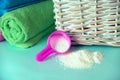 Pink plastic measuring vessel with washing powder, containers with detergent, stack terry towels