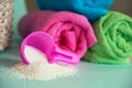 Pink plastic measuring vessel with washing powder, containers with detergent, stack terry towels