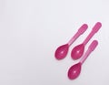 Pink plastic spoons on white background