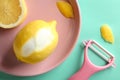 Pink plate with lemon and zester on color background