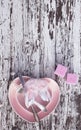 Pink plate in the shape of a heart with silver knife and fork, candles and decorative wings on white wooden background. Top view. Royalty Free Stock Photo
