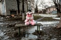 Pink plush rabbit sits on a bench in a poor residential area