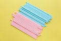 Pink polka dot paper straws and light blue polka dot paper straws on yellow background. Drinking straws, Royalty Free Stock Photo