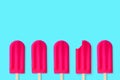 Pink popsciles on a pastel blue background. One with bite removed. Royalty Free Stock Photo