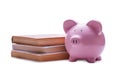 Pink porcelain piggy bank near a pile of old books Royalty Free Stock Photo