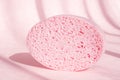 Pink porous sponge for bath on pink background with shadows. Royalty Free Stock Photo