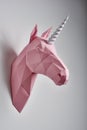 Pink powder coloured unicorn hanging on white wall.