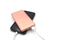 Pink power bank is connected by cable to the phone on a white background. Charging your phone from a power bank Royalty Free Stock Photo
