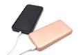 Pink power bank is connected by cable to the phone on a white background. Charging your phone from a power bank