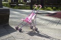 Pink pram stands alone in the park.