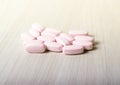 Pink probiotic pills or vitamins on a wooden background.