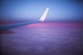 Pink and purple fluffy clouds on the sunrise under the wing of the airplane, window view high in the sky, photo Royalty Free Stock Photo