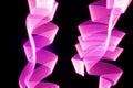 Pink and purple glow neon wave of light as curls or swirl with smooth stripes on black background, pattern Royalty Free Stock Photo