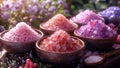 Pink and purple Himalayan salts in bowls on table with flowers Royalty Free Stock Photo