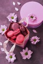 Pink and purple macaroon close-up in a gift paper bag on a purple background decorated with flowers. Top view, selective focus. Royalty Free Stock Photo