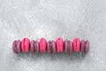 Pink and purple macaroons in a row on a gray background. Top view, copy space