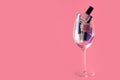 Pink, purple nail polish bottles set. Nail polish bottles in wine glass. Purple nail polsih bottles on pink background Royalty Free Stock Photo