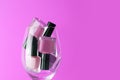 Pink, purple nail polish bottles set. Nail polish bottles in wine glass. Purple nail polsih bottles on pink background Royalty Free Stock Photo