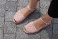 Pink-purple sandals on a girl's feet on a gray granite background.
