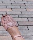 Pink-purple sandals on a girl's feet on a gray granite background.