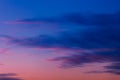 Pink and purple sunset sky with clouds painted in dark tones of blue