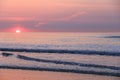 Pink and purple tints with sun peeking over horizon of ocean sunrise