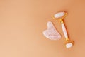 Pink quartz jade roller and gua sha tool stone on modern beige background. Trendy beauty tool. Minimal composition, copy space,