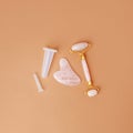 Pink quartz jade roller and gua sha tool stone on modern beige background. Trendy beauty tool. Minimal composition, copy space,