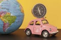 Pink retro car and compass with world globe sphere on yellow background, close-up toned photo Royalty Free Stock Photo