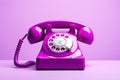 Pink retro phone on purple background. 80s or 90s retro fashion aesthetic. Retro object, gadget, telephone.