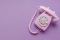 Pink retro phone on purple background. 80s or 90s retro fashion aesthetic. Retro object, gadget, telephone.