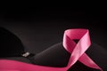 Pink ribbon on a black bra against a dark background to support a breast mammary cancer awareness campaign in october