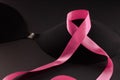 Pink ribbon on a black bra against a dark background to support a breast mammary cancer awareness campaign in october