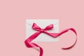 Pink ribbon bow on a white envelope on a pink background Royalty Free Stock Photo