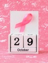 Pink ribbon of breast cancer awareness on a white wooden perpetual calendar with date 29 october. International breast cancer